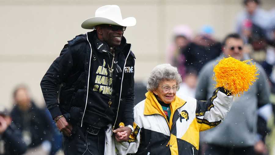 Colorado Buffaloes head coach Deion Sanders holds Peggy Coppom's hand before the Buffs' spring game at Folsom Field.