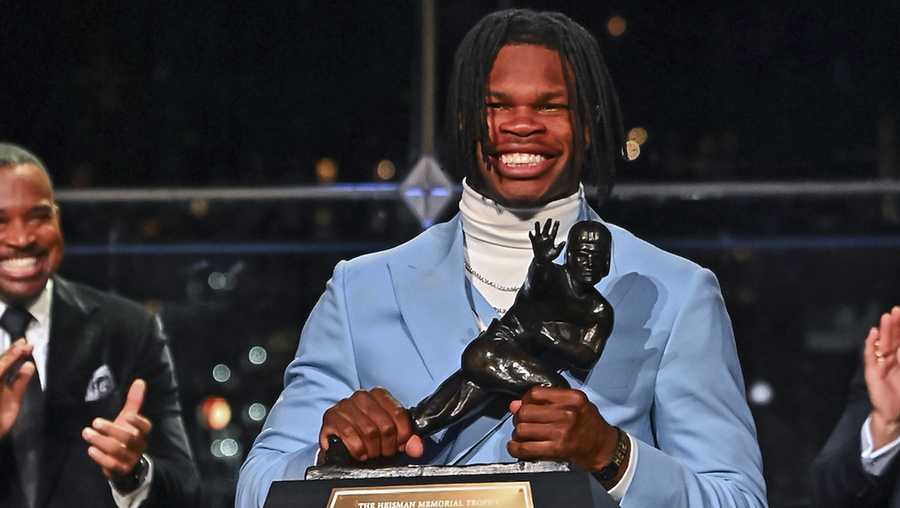 Colorado’s Travis Hunter holds the trophy after winning the Heisman Trophy as the outstanding player in college football, Saturday, Dec. 14, 2024, in New York.