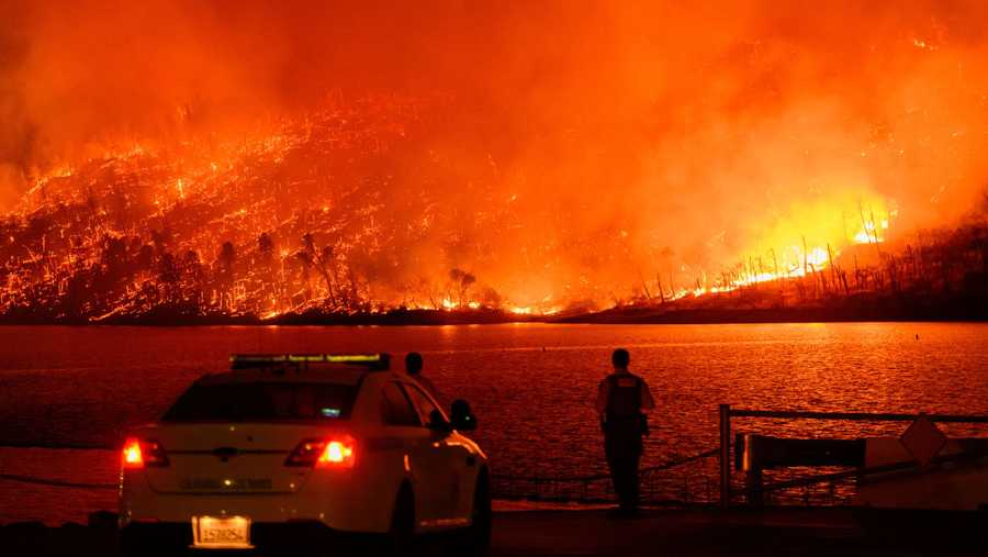 TOPSHOT - Law enforcement members watch as the Thompson fire burns over Lake Oroville in Oroville, California on July 2, 2024. A heatwave is sending temperatures soaring resulting in red flag fire warnings throughout the state. (Photo by JOSH EDELSON / AFP) (Photo by JOSH EDELSON/AFP via Getty Images)